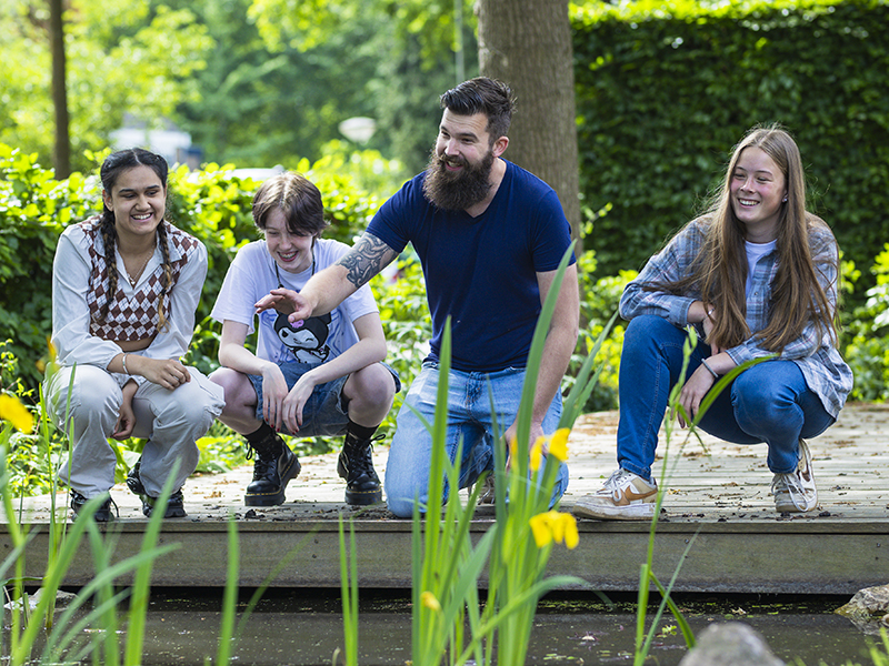 man wijst vanaf waterkant naar planten