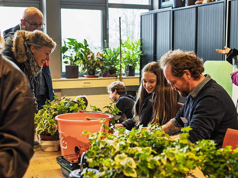 ouders en leerlingen achter een tafel met bloemen